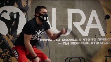  Spor salonundaki adam maskeli halatlarla meşgul.