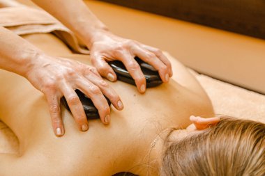 Taş terapisi. Şirin kıza taşlarla masaj yapılıyor.