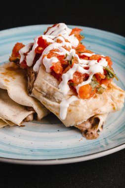 Meksika baharatlı yemekleri tabakta, yanında kırmızı biber ve vişneli domatesler var..