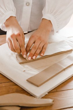 Kadın elleri çömlekçide masanın üzerinde merdaneyle killeri yuvarlıyor.