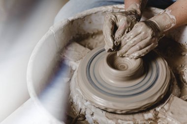 Kadın elleri kil tabaklarını yontuyor. Fotoğraf ve mercek parlaması