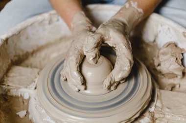 Kadın elleri kilden bir kupa yontuyor.