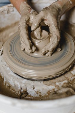 Kadın elleri kilden bir kupa yontuyor.