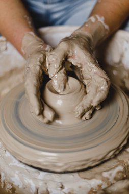 Kadın elleri kilden bir kupa yontuyor.