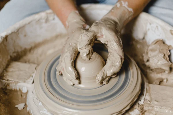 Kadın elleri kilden bir kupa yontuyor.