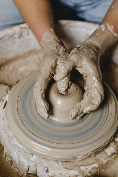 Kadın elleri kilden bir kupa yontuyor.