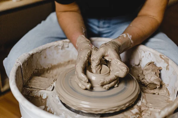 Kadın elleri kilden bir kupa yontuyor.