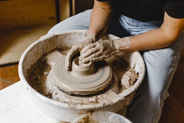Kadın elleri kilden bir kupa yontuyor.