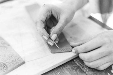 Kadın elleri çömlek atölyesindeki bir derste kilden güzel tabaklar yontuyor.