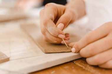 Kadın elleri çömlek atölyesindeki bir derste kilden güzel tabaklar yontuyor.