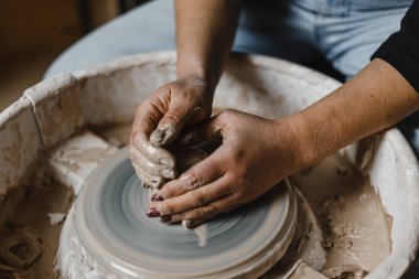 Kadın elleri çömlek atölyesindeki bir derste kilden güzel tabaklar yontuyor.