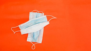 Koronavirüsten koruyucu maskeler kırmızı arkaplanda yatar