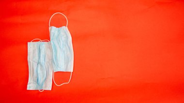 Koronavirüsten koruyucu maskeler kırmızı arkaplanda yatar