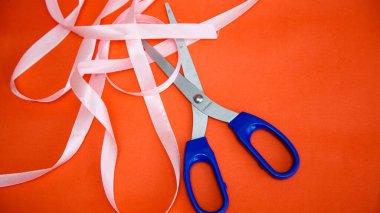 Kırmızı arka planda makas ve şenlik kurdelesi var. Sevgililer Günü için hazırlanıyor