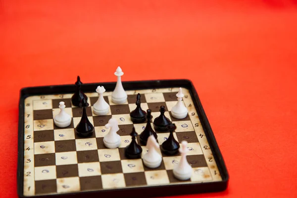 用红色背景的棋子在棋盘上旅行 国际象棋比赛白人对黑人的棋子 — 图库照片