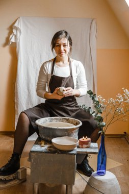 Potter kızı çömlekçi çarkında kilden kupa yontuyor. Öğleden sonra çömlek atölyesi