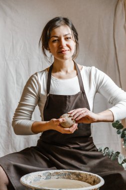 Potter kızı çömlekçi çarkında kilden kupa yontuyor. Öğleden sonra çömlek atölyesi