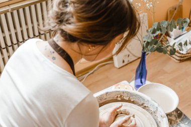 Potter kızı çömlekçi çarkında kilden kupa yontuyor. Öğleden sonra çömlek atölyesi