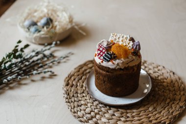 Bayram boyalı Paskalya bir tabakta, arka planda bir söğüt dalı ve boyalı yumurtalarla dolu bir sepet var.