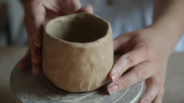 Kadın seramikçi elleri mumlarla kil tabakları yontuyor.