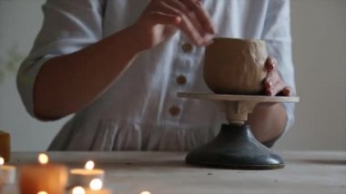 Kadın seramikçi elleri mumlarla kil tabakları yontuyor.