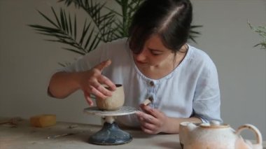 Kadın seramikçi elleri mumlarla kil tabakları yontuyor.