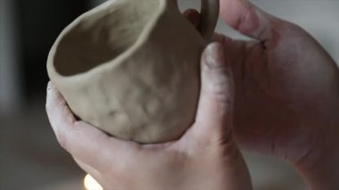 Kadın seramikçi elleri mumlarla kil tabakları yontuyor.