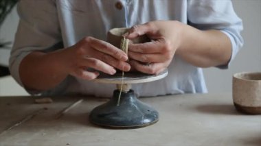 Kadın seramikçi elleri mumlarla kil tabakları yontuyor.