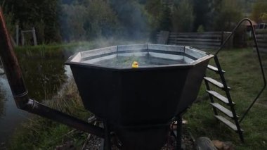 Dağların ve ormanların ortasında dumanı tüten sıcak su fıçısı