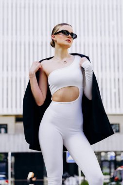 İnce, güzel sarışın manken yazın sokakta poz verir.