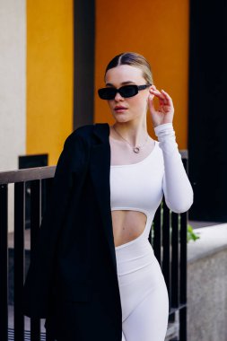 İnce, güzel sarışın manken yazın sokakta poz verir.