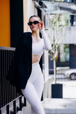 İnce, güzel sarışın manken yazın sokakta poz verir.