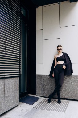 İnce, güzel sarışın manken yazın sokakta poz verir.