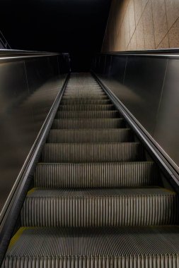 Boş yürüyen merdiven modern iç mekanda karanlığa doğru yol alıyor. Yüksek kalite fotoğraf