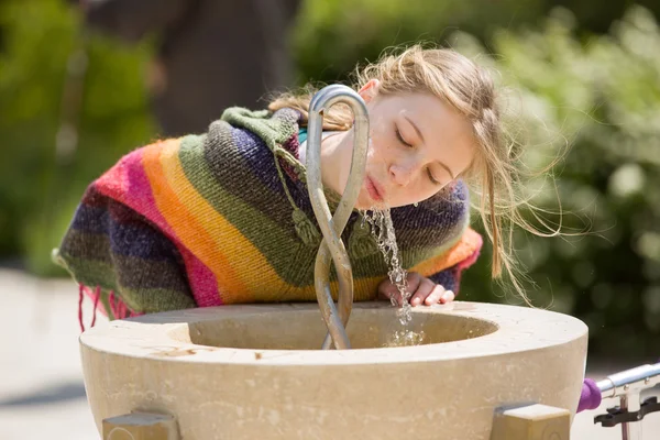 Blonde jeune fille boit à la fontaine publique — Photo
