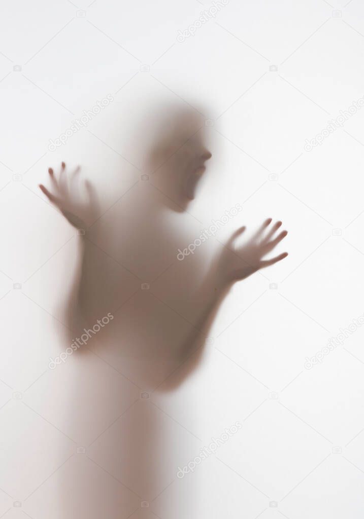 Scary diffuse human face and hands silhouette shouting behind a curtain