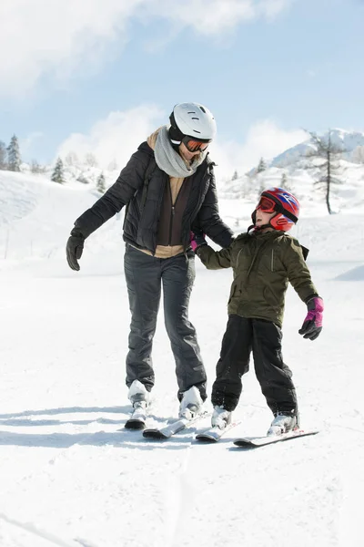 어미와 아들은 겨울에 눈덮인 산비탈에서 스키를 배운다 로열티 프리 스톡 이미지