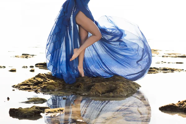 Longo azul vestido pernas de mulher magra na praia — Fotografia de Stock