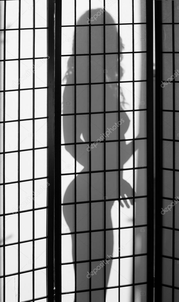 Beautiful naked woman silhouette behind a folding screen
