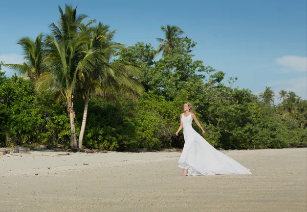 Mulher bonita em branco vestido longo corre na praia — Fotografia de Stock