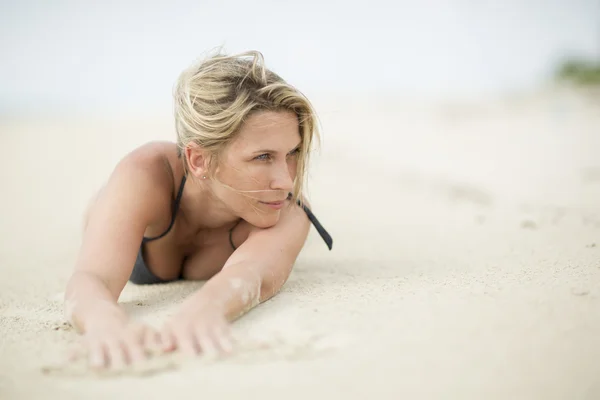 Sandy ręce. Piękne blond kobieta kładzie się na plaży. — Zdjęcie stockowe