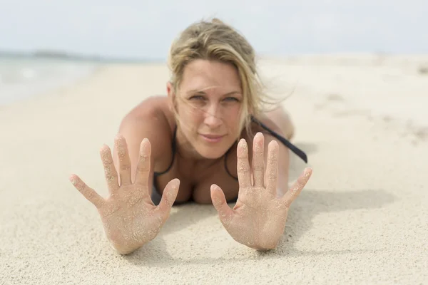 Sandy ręce. Piękne blond kobieta kładzie się na plaży. — Zdjęcie stockowe