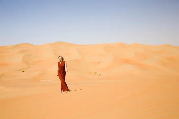 Long dressed woman walks in desert — Stock Photo, Image