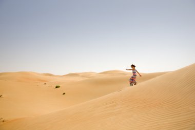 Çölde kum tepeleri arasında genç kız oynar