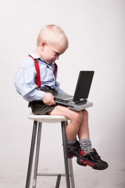 Little blonde boy sits on chair with portable dvd player clipart