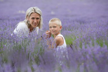 Blonde mother and her son together in lavender field clipart