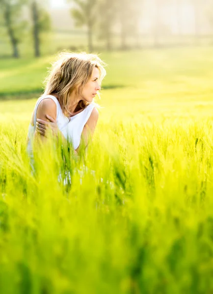 Beautiful blonde woman sits in the middle of a field — Stock Photo, Image
