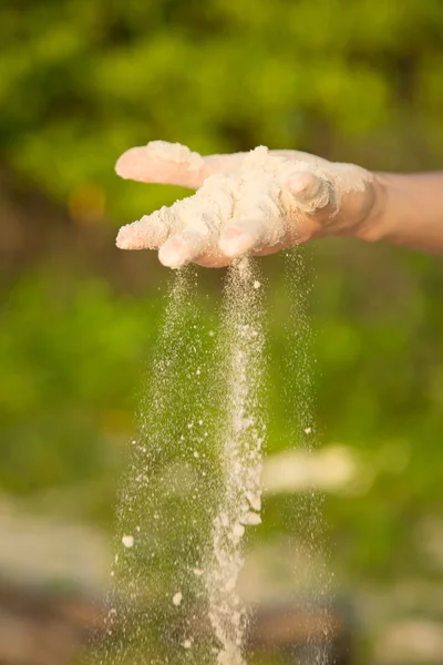 Mano, con arena que cae al aire libre, fondo de planta verde —  Fotos de Stock