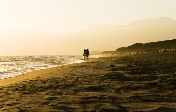 Ló-lovas pár sunset Beach, a tenger mellett — Stock Fotó