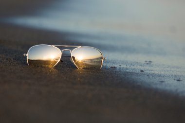 Güneş gözlüğü kumlu Plajı'nda batan güneşin ışığını yansıtmak